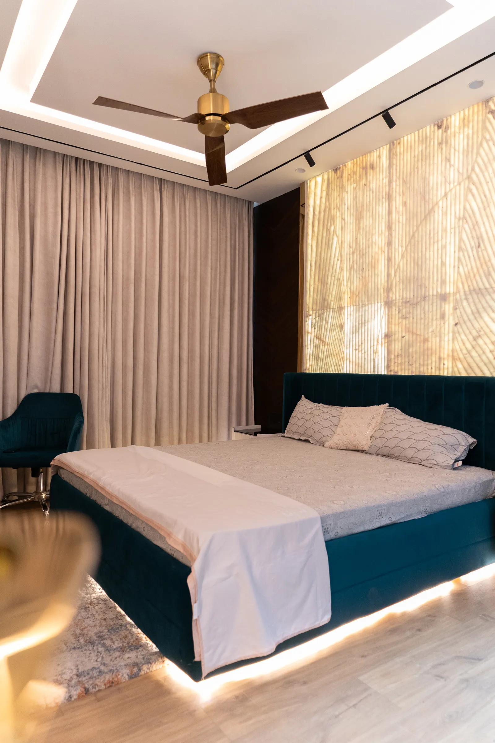 Master bedroom with teal bed, cove lighting and backlit onyx wall — Abhishek's Residence